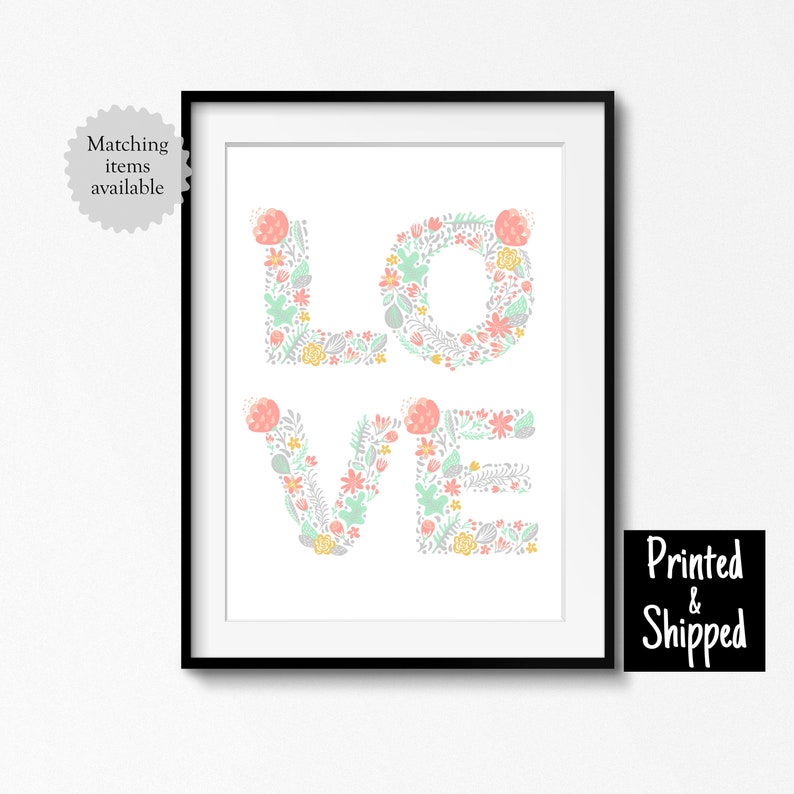 May include: A framed print with the word "LOVE" spelled out in large letters. Each letter is made up of a floral pattern in shades of pink, green, and yellow.