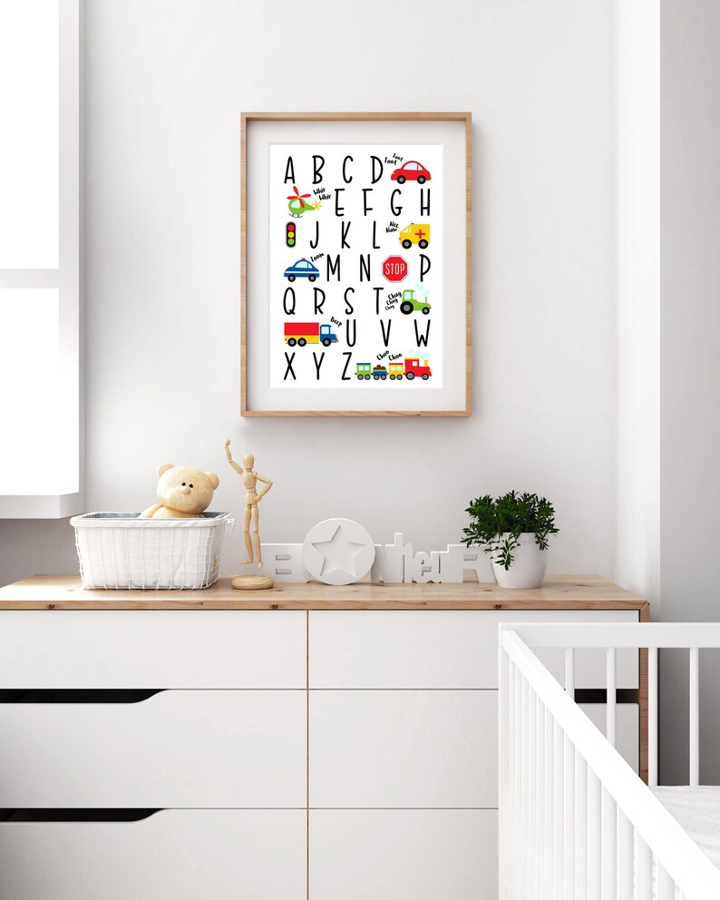May include: A white framed alphabet chart with colorful illustrations of vehicles and transportation. The letters are black and the words below each letter are in a smaller font. The letters are A through Z.