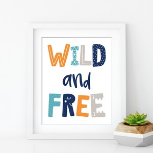 May include: White framed print with the text "WILD and FREE" in colorful, patterned letters. The letters are in shades of orange, blue, and gray.
