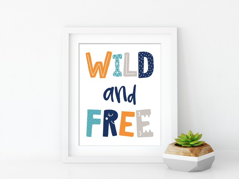 May include: White framed print with the text "WILD and FREE" in colorful, patterned letters. The letters are in shades of orange, blue, and gray.