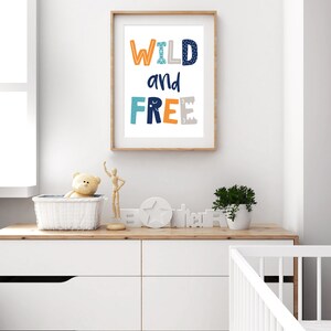 May include: A framed print with the text "WILD and FREE" in blue, orange, and gray letters. The letters have a geometric pattern and are set against a white background.