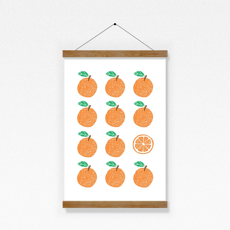 May include: A white framed print with a pattern of 12 orange oranges with green leaves and one orange slice. The oranges are arranged in a grid pattern.