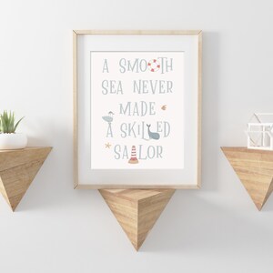May include: A framed print with a nautical theme. The print features the text "A smooth sea never made a skilled sailor" with illustrations of a seagull, a whale, a life preserver, a starfish, and a lighthouse.