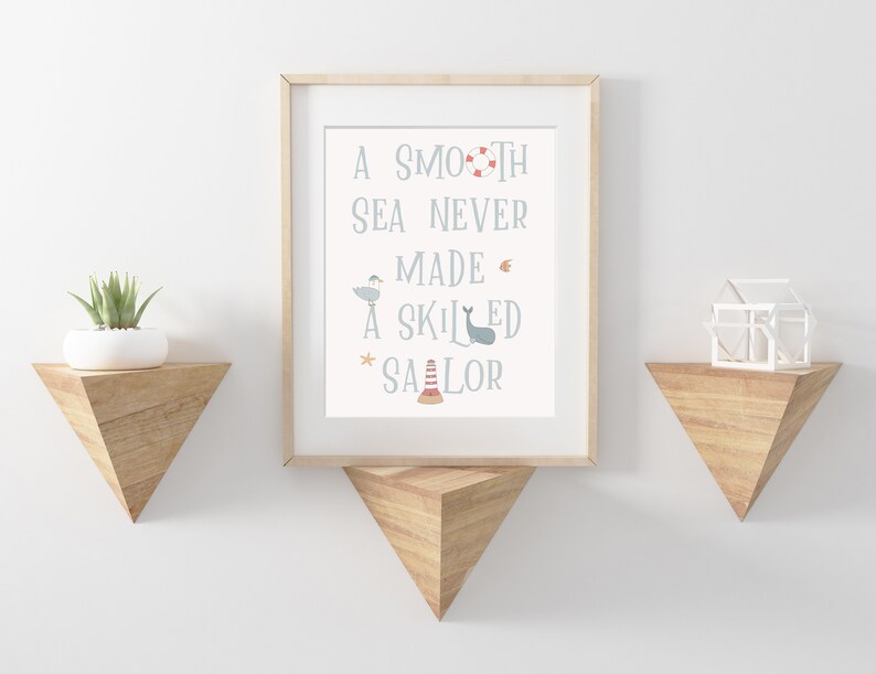 May include: A framed print with a nautical theme. The print features the text "A smooth sea never made a skilled sailor" with illustrations of a seagull, a whale, a life preserver, a starfish, and a lighthouse.
