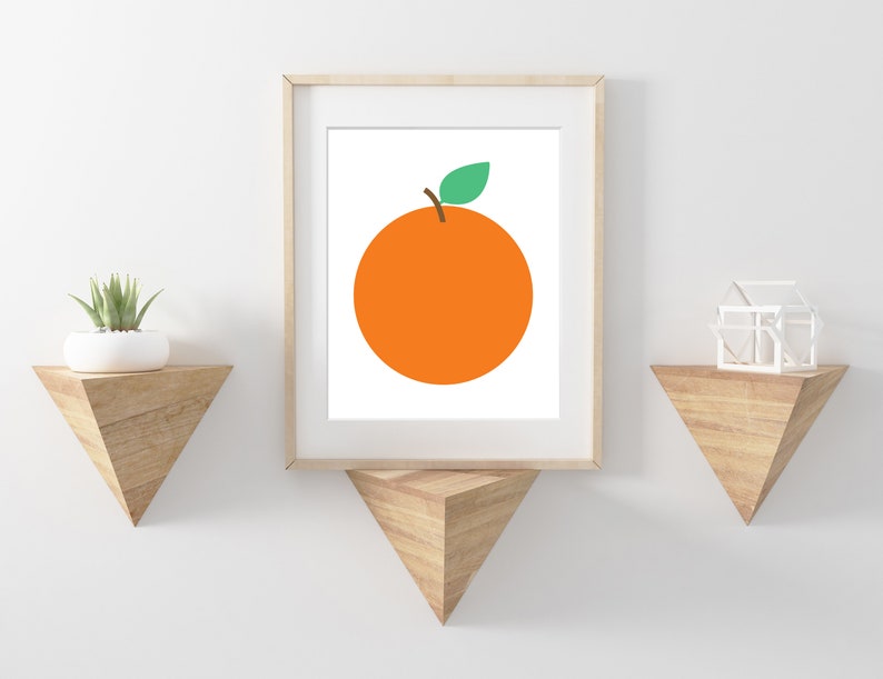 Puede incluir: Una impresi&oacute;n enmarcada de una naranja simple con una hoja verde sobre un fondo blanco. La impresi&oacute;n est&aacute; colgada en una pared blanca con dos estantes de madera triangulares.