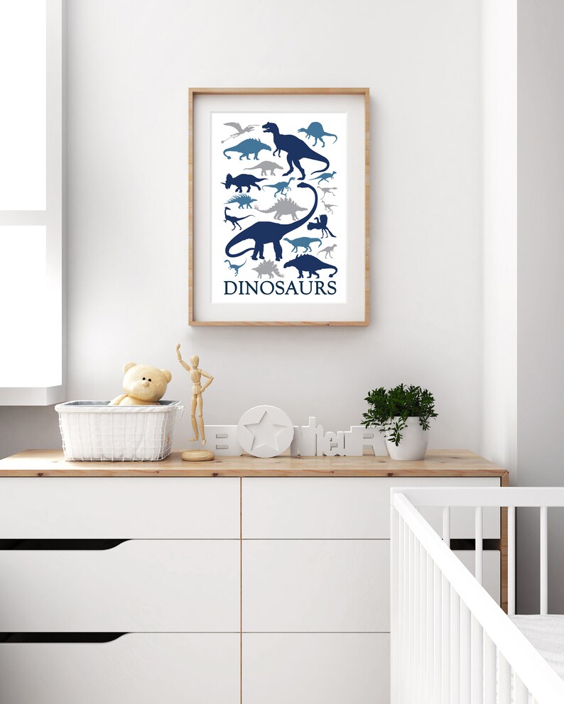 May include: A framed print with a white background and blue dinosaur silhouettes. The print has the word "DINOSAURS" at the bottom.