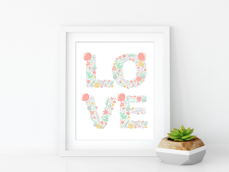 May include: A white framed print with the word "LOVE" spelled out in pastel pink, green, and gray floral designs.