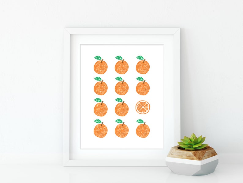 May include: A white framed print with a pattern of 12 orange fruits, all but one are whole, the last one is a slice of orange. The print is on a white background.