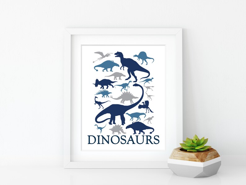 May include: A white framed print with a blue and gray silhouette of various dinosaurs. The print has the word "DINOSAURS" at the bottom.