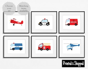 May include: Six printable wall art prints featuring illustrations of various vehicles, including a red airplane, a black and white police car, a red ambulance, a blue police van, a red fire truck, and a blue helicopter. The prints are framed in black frames and have white backgrounds.