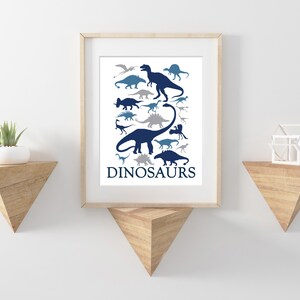 May include: A framed print with a white background and blue and gray dinosaur silhouettes. The print has the word "DINOSAURS" at the bottom.