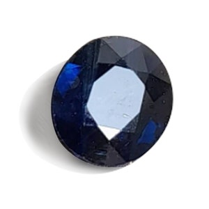 May include: A dark blue sapphire gemstone with a round cut and a faceted design.