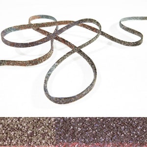 Peut inclure: Un ruban de près, de couleur marron, gris et bleu. Le ruban est tissé avec un léger scintillement et a une surface légèrement texturée.