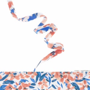 Peut inclure: Un ruban blanc avec un motif floral bleu et rose est enroulé et tordu. Le ruban est sur un fond blanc.
