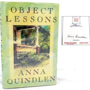 May include: A green hardcover book with the title "Object Lessons" by Anna Quindlen. The book cover features a watercolor painting of a porch with a brick column and green foliage.