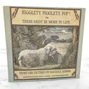 May include: A vintage book titled "Higglety Pigglety Pop!" by Maurice Sendak. The cover features an illustration of a fluffy dog with a suitcase in a forest scene. The book is published by Harper & Row, established in 1817.