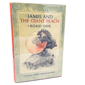 May include: A hardcover book titled "James and the Giant Peach" by Roald Dahl. The cover features an illustration of a peach, a tree, and a small figure. The book has a green and orange cover.