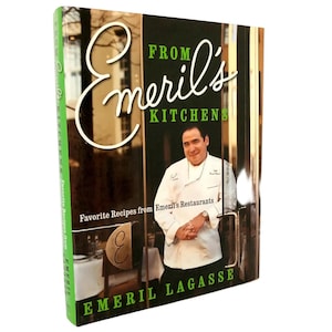 以下が含まれることがあります： 「From Emeril's Kitchens」というタイトルの料理本。表紙にはシェフのエメリル・ラガッセの写真が写っています。表紙は濃い緑色で、白い文字と白いコックコートを着たシェフの写真が写っています。本の背表紙は緑色で白い文字が書かれています。