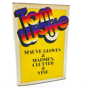 May include: A hardcover book with a bright yellow cover featuring the title Tom Wolfe in large, bold, multi-colored striped letters. Below the title, the text reads Mauve Gloves & Madmen, Clutter & Vine in black serif font on a yellow background.