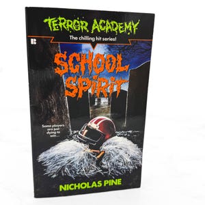 May include: A paperback book titled Terror Academy: School Spirit by Nicholas Pine. The cover features a red football helmet resting on white pom-poms against a dark graveyard background. The text reads The chilling hit series and Some players are just dying to win.