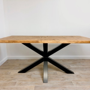 May include: A wooden dining table with a natural finish and a black metal X-shaped base.