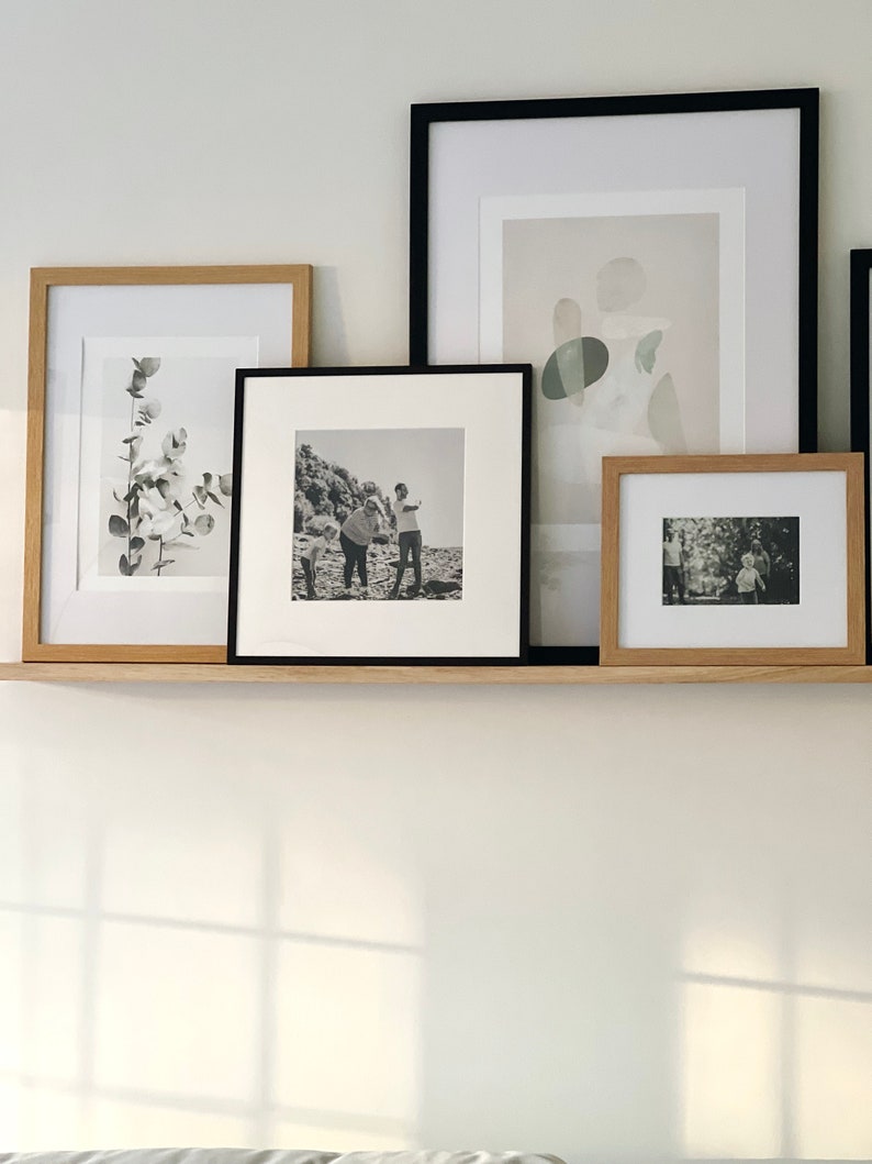 May include: Four framed pictures on a shelf. The pictures are in black and white and feature a variety of subjects, including a plant, a family, and abstract shapes.