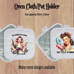 May include: Two white oven gloves with a quilted grey backing. One glove features a vintage illustration of a woman with a glass of wine and the text "The dishes are looking dirty at me again". The other glove features a vintage illustration of a woman with a wink and the text "Too hot to handle".