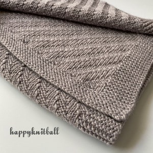 May include: A soft, gray knitted blanket with a chevron pattern. The blanket is folded in half and the edges are visible.