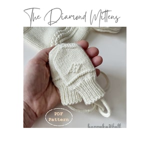 May include: A pair of small, off-white knitted mittens featuring a textured diamond pattern on the back of the hand and a ribbed cuff. The text "The Diamond Mittens" and "PDF Pattern" are visible in the image, along with the brand name "happyknitball".