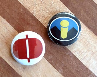 May include: Two round pinback buttons. One button has a red oval with a white vertical line and a white horizontal line. The other button has a black background with a yellow microphone design, blue sky, and black mountains.