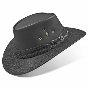 Op de afbeelding: Een zwarte leren cowboyhoed met een gevlochten band en een reli&euml;fpatroon van bloemen. De hoed heeft een kroon met een klein metalen leeuwenkopembleem en vier metalen oogjes.