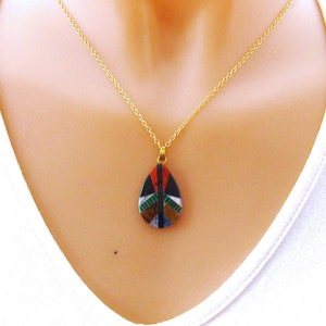 May include: A gold chain necklace with a teardrop-shaped pendant. The pendant is made of colorful mosaic tiles in shades of blue, green, red, black, and white.