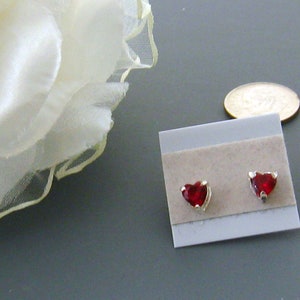 May include: A pair of heart-shaped earrings with red gemstones set in silver.