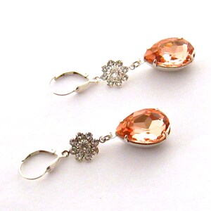May include: A pair of peach-colored teardrop-shaped crystal earrings with silver-toned settings and a small flower-shaped crystal cluster on the top of each earring.