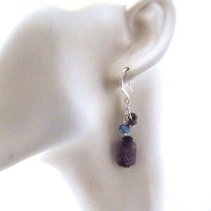 May include: Silver dangle earrings with a purple, blue and black gemstone cluster.