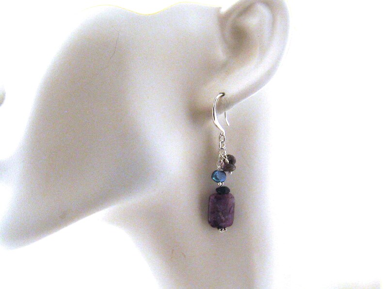 May include: Silver dangle earrings with a purple, blue and black gemstone cluster.