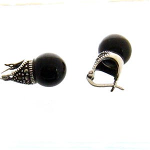 May include: A pair of black onyx earrings with silver marquise-shaped settings. The earrings have a simple, elegant design.
