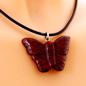 May include: A red butterfly pendant necklace with a black leather cord.