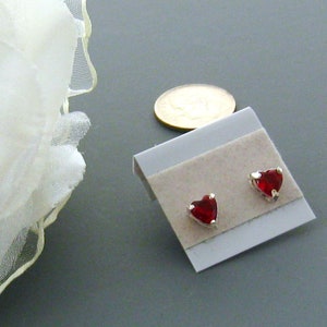 May include: A pair of silver stud earrings with red heart-shaped stones.