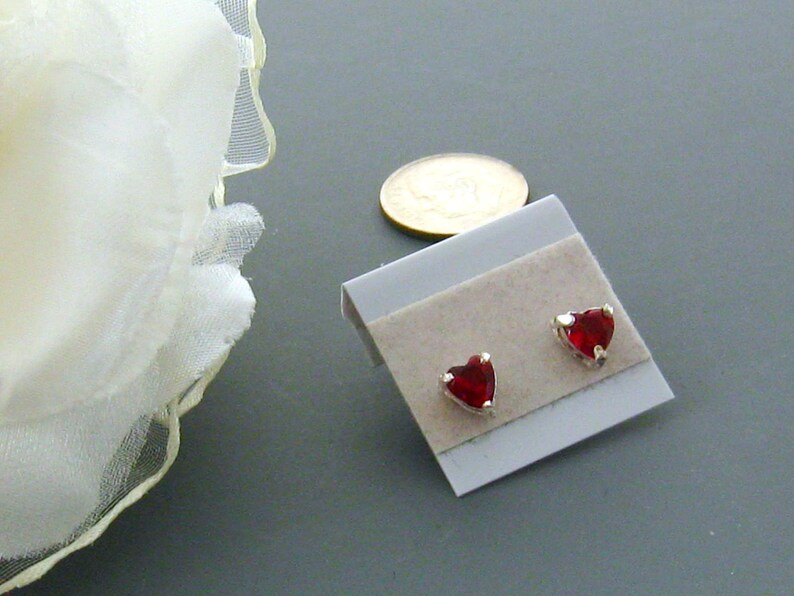 May include: A pair of silver stud earrings with red heart-shaped stones.