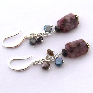 May include: A pair of silver earrings with a pink and white rectangular stone and a cluster of dark grey and brown beads.