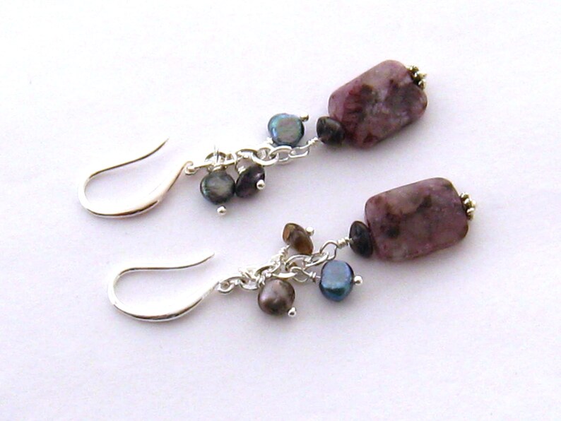 May include: A pair of silver earrings with a pink and white rectangular stone and a cluster of dark grey and brown beads.