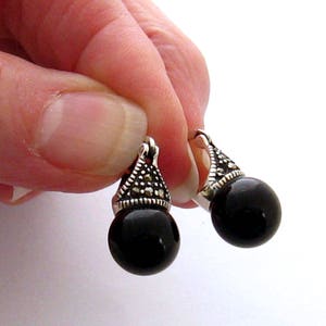 May include: A pair of black onyx drop earrings with silver marquise-shaped settings accented with marcasite stones.