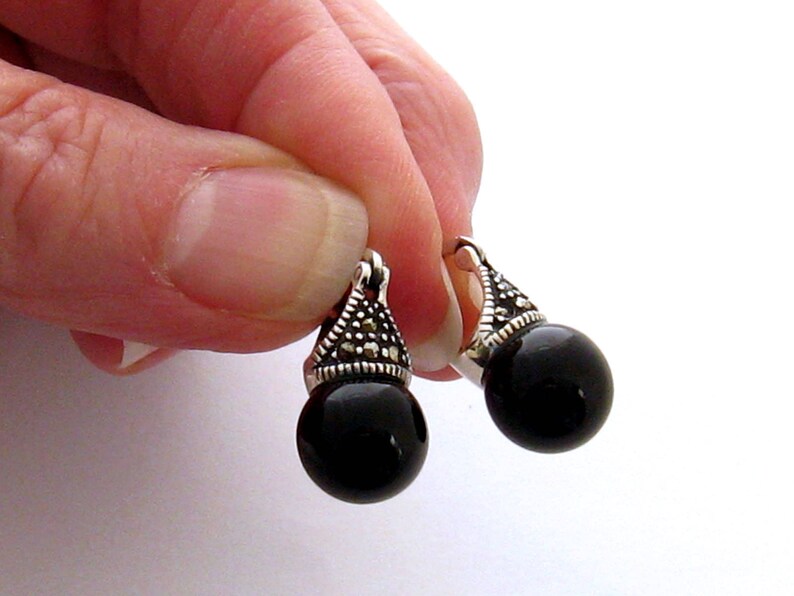 May include: A pair of black onyx drop earrings with silver marquise-shaped settings accented with marcasite stones.