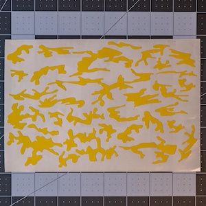 Może przedstawiać: Żółta arkusz szablonu z wzorem kamuflażu. Szablon jest przeznaczony do malowania lub aerografu.