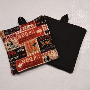 May include: Two red and black pot holders with a BBQ theme. The front side features a patchwork design with various BBQ-related phrases and images, including "BBQ", "Almost There", "Bar-B-Que Forever", and "Weekend BBQ Chef". The back side is solid black.