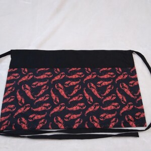 May include: Black apron with red lobster print and two black ties.