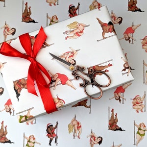 May include: Red and white wrapping paper featuring a pattern of women in various poses on a pole. The paper is decorated with a red bow and a pair of silver scissors.