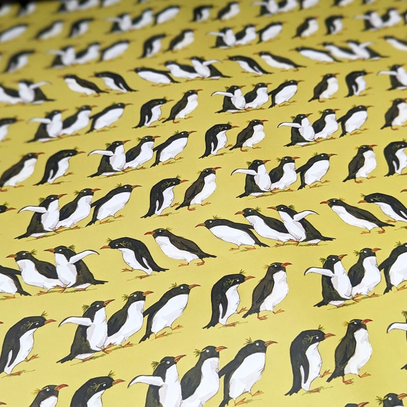 Puede incluir: Un fondo amarillo con un patr&oacute;n repetitivo de ping&uuml;inos negros y blancos. Los ping&uuml;inos est&aacute;n mirando en diferentes direcciones y algunos est&aacute;n en pleno vuelo.
