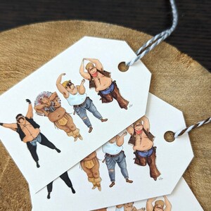 May include: Several white gift tags with illustrations of men in various costumes, including a cowboy, a Native American, and a construction worker. The tags are tied with a gray and white string, and are set against a brown background.